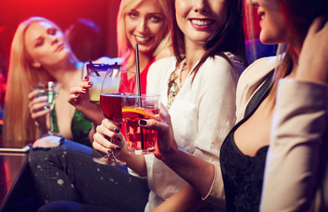 Smiling girls in the club toast cocktails