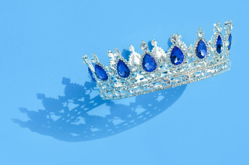 Silberne Krone mit blauen Steinen im Sonnenlicht auf blauem Hintergrund Adel Krönung Jubiläum © Goldengel