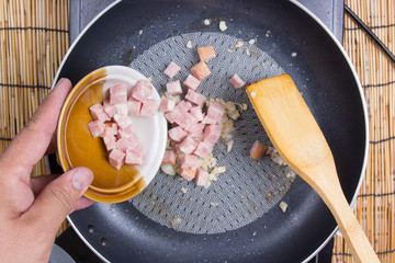 Chef putting bacon to the pan cooking