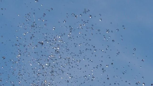 Брызги фонтана/ Брызги фонтана крупым планом на фоне синего неба
