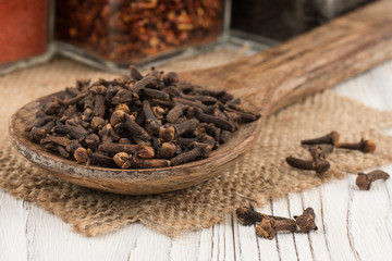 Spice cloves in a wooden spoon on old wooden table.