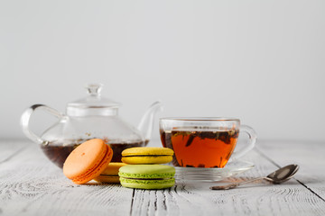 Colorful macaroons with cup of tea on color wooden table
