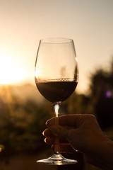 Weinglas in Frauenhand, Abendsonne mit Sonnenstrahlen