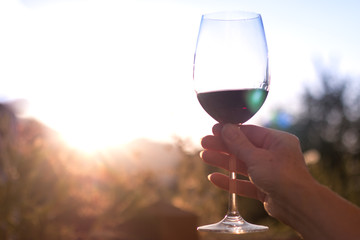 Weinglas in Frauenhand, Abendsonne mit Sonnenstrahlen