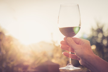 Weinglas in Frauenhand, Abendsonne mit Sonnenstrahlen