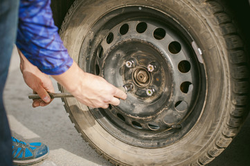 man changing a wheel on the road. on way there was breakage of wheel, puncture,  necessary to lift the car jack and remove the wheel by loosening the nuts. road problems travelers. do it yourself