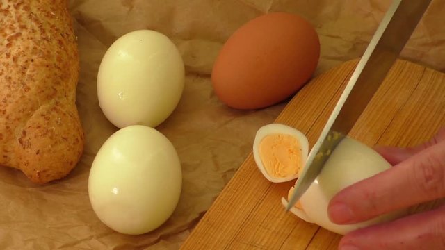 Slicing egg on a wooden cutting board 
