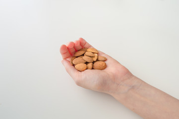 Woman Holding Almonds in Her Hand on a White Background