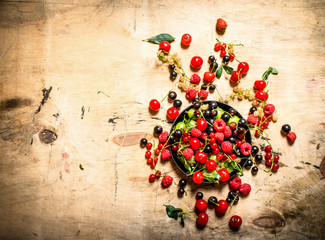 Wild berries in the old plate. On wooden table.