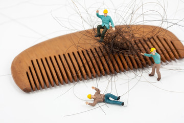 selective focus photo of miniature workers holding hair loss from wooden comb, abstract background...