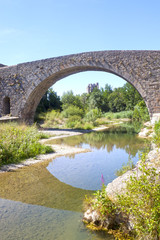 Fototapeta na wymiar Bridge in Lagrasse with the abbey behind and the reflection in the river