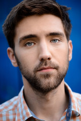 Close up portrait of handsome man thinking over blue background.