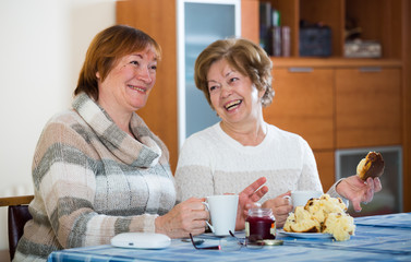 Female pensioners watching TV channel and drinking tea