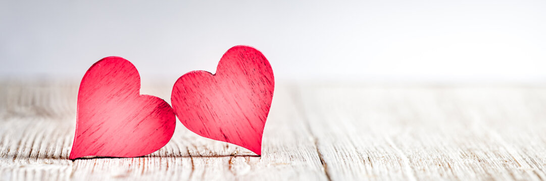 Two red hearts on wooden background