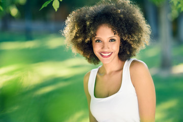 Young black woman with afro hairstyle smiling in urban park