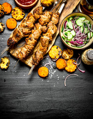 Shish kebab on skewers with grilled vegetables and fresh salad.