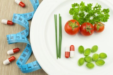 Strict diet against obesity. Dietary vegetable diet. Tomatoes on a plate. Raw vegetables on a white plate and a measuring tape.
