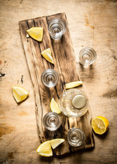 Bottle of vodka with shot glasses and lemon.