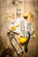 Bottle of vodka with shot glasses and lemon.