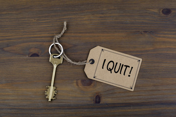 Key and a note on a wooden table with text - I Quit!