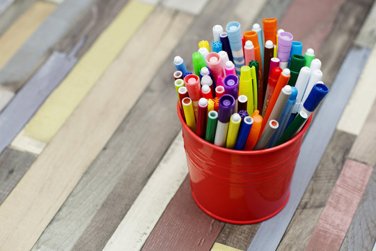 Colored markers in a metal bucket. Different children's felt  pens for painting on wooden background. 