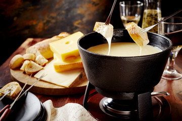 Dipping into a delicious cheese fondue - obrazy, fototapety, plakaty