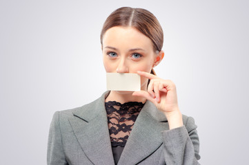 Lady with business card. Confident young woman holding business card in front of her mouth card in her hand and while standing isolated studio background