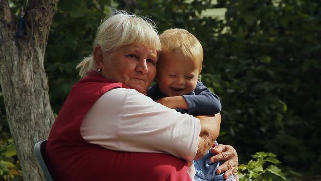Grandma happily hugging little grandson in the garden