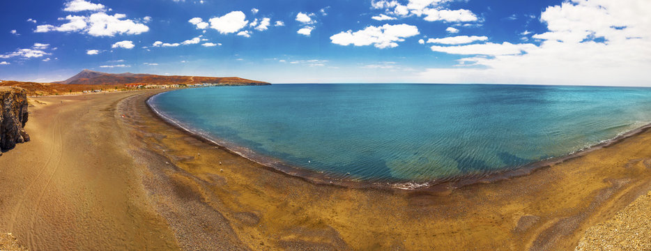 Black sandy beach with vulcanic mountains in the background in Tarajalejo on Fuerteventura island, Canary Islands, Spain.