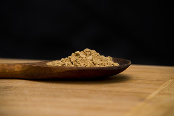 close up on powder ginger on wood with black background