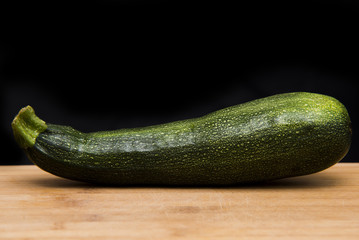  close up on Zucchini courgette on wood and black background