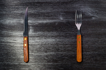 Fork and Knife on Black Wood Texture Background