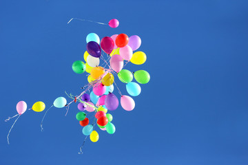 many multicolored balloons flying in the blue sky