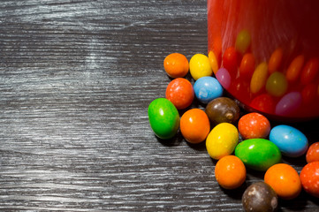 Obraz premium Colorful candy surround of red cup on black wooden texture backg