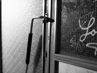 Alte Haustür im Stil der Nachkriegszeit mit Riffelglas mit Graffiti im Sonnenschein an der...