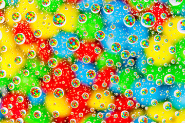 Rainbow color chocolate lentils focused in water drops