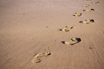 Footprints in the sand on Polzeath beach Vintage Retro Filter.