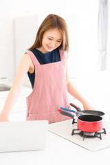 パソコンを見ながら料理をする女性