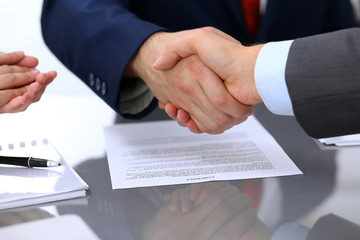 Obraz premium Two business man shaking hands to each other above signed contract