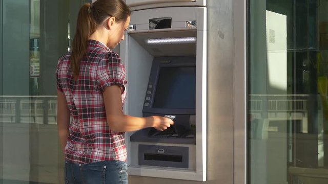Woman inserts banking card in ATM