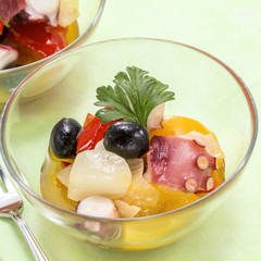 Sauteed octopus with olive, onion and tomatoes in glass bowl