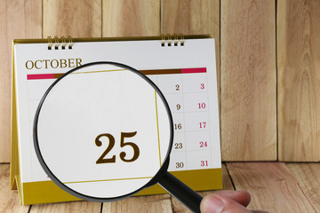 Magnifying glass in hand on calendar you can look Twenty Five da