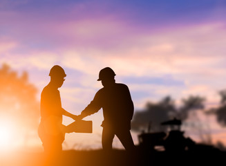 Silhouette engineer construction industry stands shake hands wit