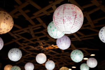  Many white round Chinese paper lanterns hanging in the darkness