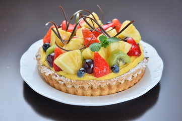 Cake of fruit with strawberry pineapple grape kiwi on white plat