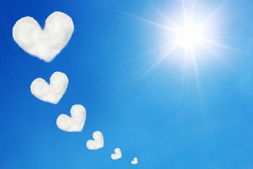 heart shaped clouds on blue sky and sun shines