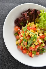 Special salad with corn tomato and herbs on white plate in resta