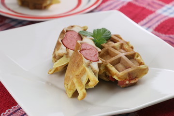 French hot dog with sausages and mint leaf on white plate