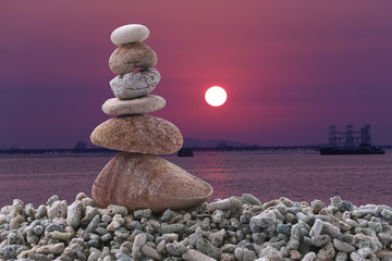 Balance stone on pile rock of sunset background in the evening.