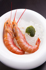 Steamed shrimps on ice on white plate with broccoli